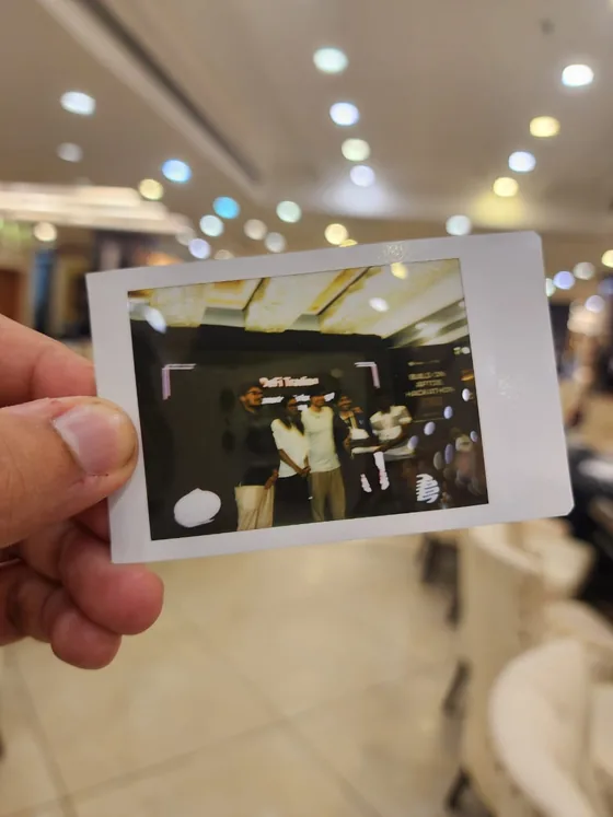 A hand holding an instant photo of the team on stage at the award