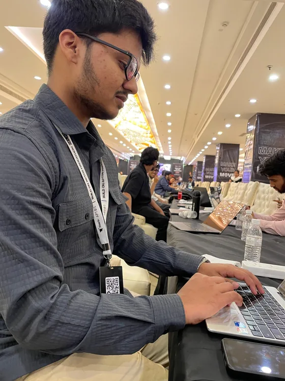 Mirza typing on his laptop, wearing a Build on Aptos lanyard