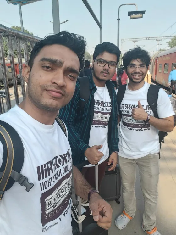 Three hackers in Blocktrain T-shirts with backpacks on the platform, one giving a thumbs up