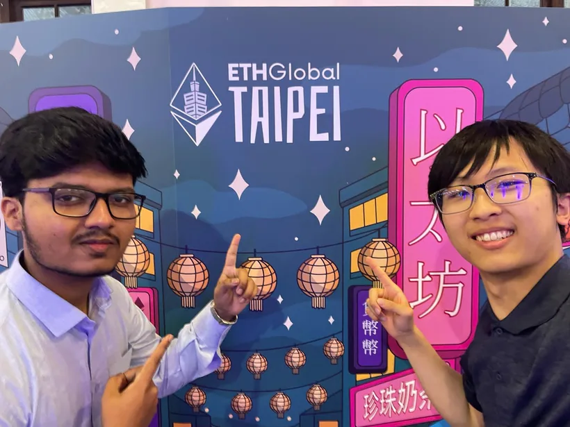 Mirza and another hacker pointing at the ETHGlobal Taipei sign on a night-market themed wall of lanterns