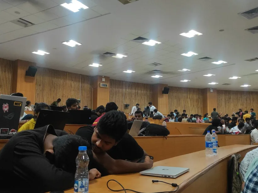 Hackers at long curved desks in a big lecture hall